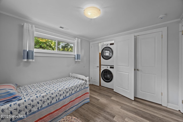 207 Battleground Ave, New Bern, NC 28560 - bedroom with estacked washer and dryer, ornamental molding, and wood finished floors