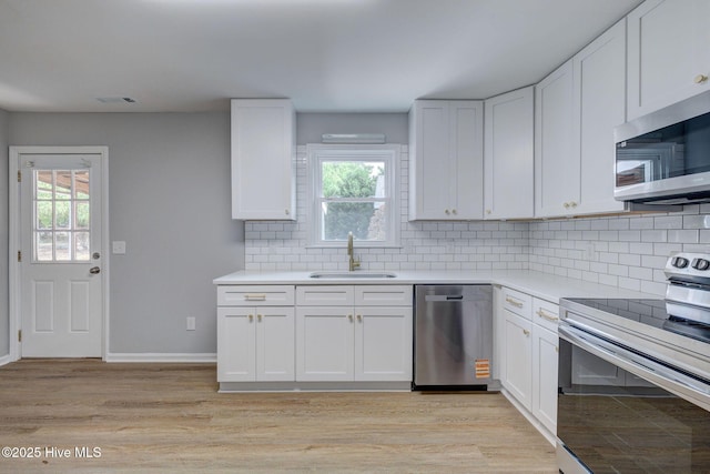 326 Cathay Rd, Wilmington, NC 28412 - kitchen featuring stainless steel appliances, a sink, white cabinets, tasteful backsplash, and plenty of natural light