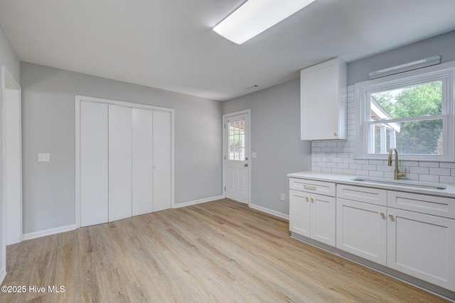 326 Cathay Rd, Wilmington, NC 28412 - kitchen featuring a sink, light wood-type flooring, light countertops, backsplash, and white cabinets