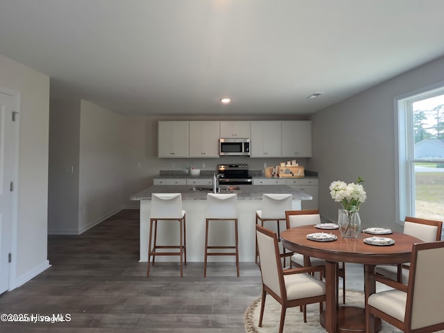 210 Presley St, Raeford, NC 28376 - kitchen with appliances with stainless steel finishes, wood finished floors, white cabinetry, a center island with sink, and recessed lighting