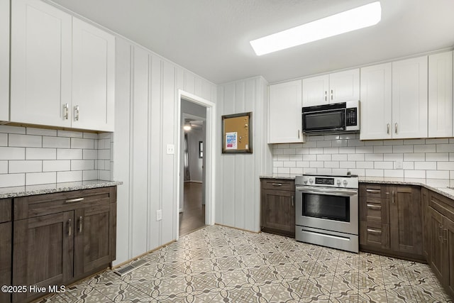 780 Leslie Campbell Ave, Lillington, NC 27546 - kitchen featuring black microwave, stainless steel electric range oven, white cabinetry, decorative backsplash, and light stone countertops