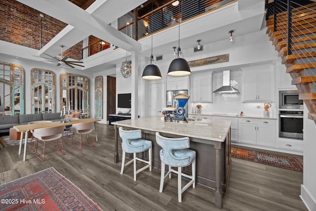 183 W Main St Unit 205, Washington, NC 27889 - kitchen featuring stainless steel appliances, wall chimney exhaust hood, a towering ceiling, dark wood-style flooring, and white cabinets