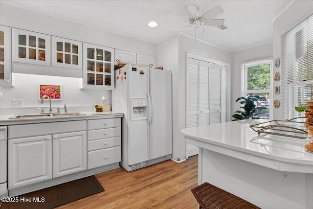 354 Sea Trail Dr E Unit 2, Sunset Beach, NC 28468 - kitchen featuring white fridge with ice dispenser, a sink, light countertops, white cabinetry, and light wood-style floors