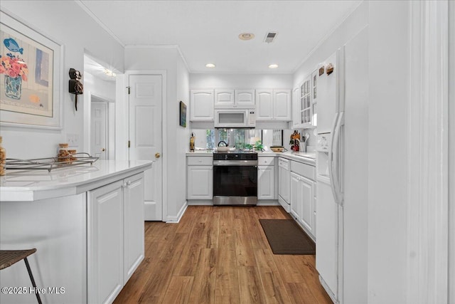 354 Sea Trail Dr E Unit 2, Sunset Beach, NC 28468 - kitchen featuring electric stove, white microwave, white cabinetry, light wood-style floors, and crown molding