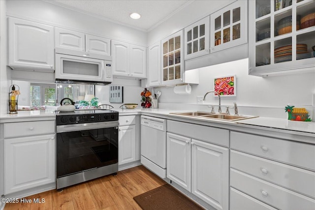 354 Sea Trail Dr E Unit 2, Sunset Beach, NC 28468 - kitchen with white appliances, a sink, white cabinetry, crown molding, and light wood-style flooring