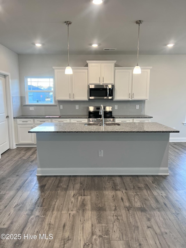 5046 Holly Hill Ct Lot 23, Battleboro, NC 27809 - kitchen featuring stainless steel appliances, a sink, an island with sink, dark stone countertops, and white cabinets
