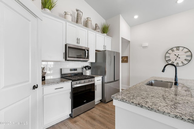 2968 Hatchers Run, Leland, NC 28451 - kitchen with stainless steel appliances, a sink, white cabinets, light stone counters, and tasteful backsplash
