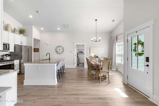 2968 Hatchers Run, Leland, NC 28451 - kitchen with stainless steel appliances, light wood-type flooring, a sink, a chandelier, and white cabinetry