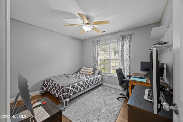 3106 John Willis Rd, New Bern, NC 28562 - bedroom with a desk, wood finished floors, baseboards, a ceiling fan, and a textured ceiling