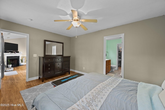 3106 John Willis Rd, New Bern, NC 28562 - bedroom featuring wood finished floors, baseboards, a fireplace, and a ceiling fan
