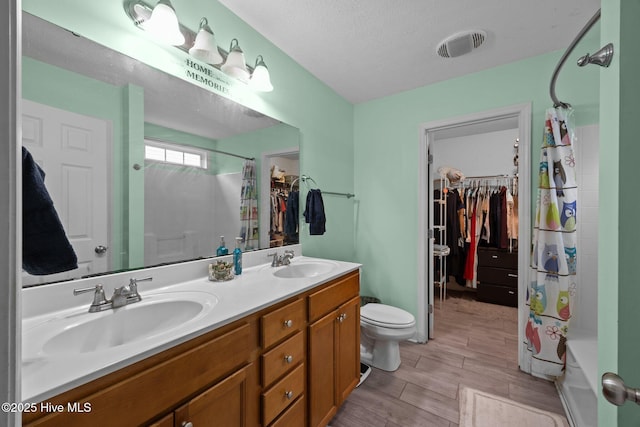3106 John Willis Rd, New Bern, NC 28562 - bathroom featuring double vanity, toilet, wood finished floors, shower / tub combo with curtain, and a spacious closet