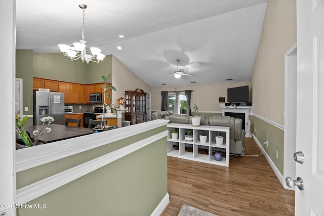 3106 John Willis Rd, New Bern, NC 28562 - kitchen featuring stainless steel appliances, brown cabinetry, lofted ceiling, a chandelier, and wood finished floors