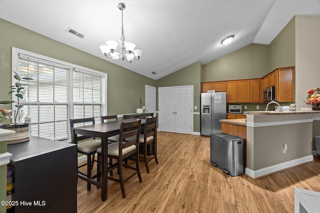 3106 John Willis Rd, New Bern, NC 28562 - kitchen featuring stainless steel appliances, a chandelier, brown cabinets, light wood-style flooring, and pendant lighting