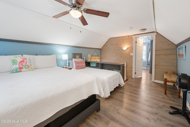 135 NE 34th St, Oak Island, NC 28465 - bedroom with wood walls, lofted ceiling, wood finished floors, and ceiling fan