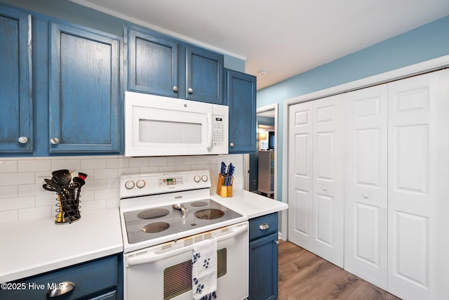 135 NE 34th St, Oak Island, NC 28465 - kitchen featuring white appliances, blue cabinetry, light countertops, backsplash, and wood finished floors