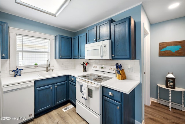 135 NE 34th St, Oak Island, NC 28465 - kitchen featuring white appliances, blue cabinets, tasteful backsplash, and light wood-style floors
