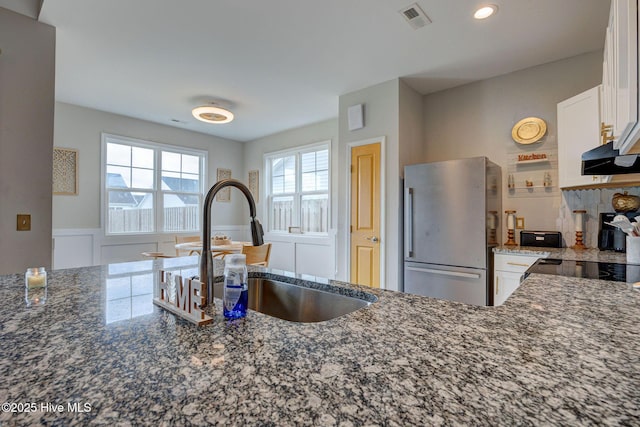 2161 Blue Bonnet Cir, Castle Hayne, NC 28429 - kitchen featuring freestanding refrigerator, dark stone counters, white cabinetry, a sink, and backsplash