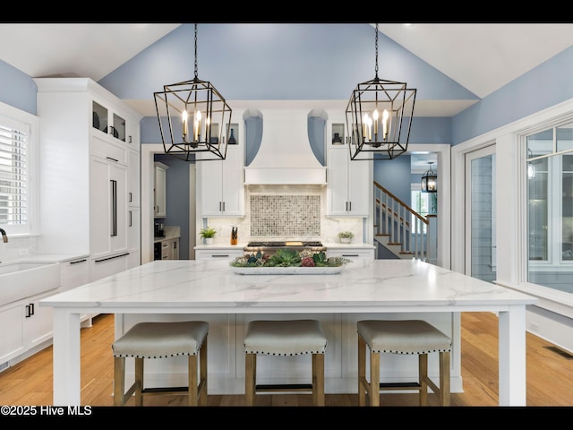 1012 Midnight Channel Rd, Wilmington, NC 28403 - kitchen featuring a chandelier, custom exhaust hood, glass insert cabinets, decorative backsplash, and high vaulted ceiling
