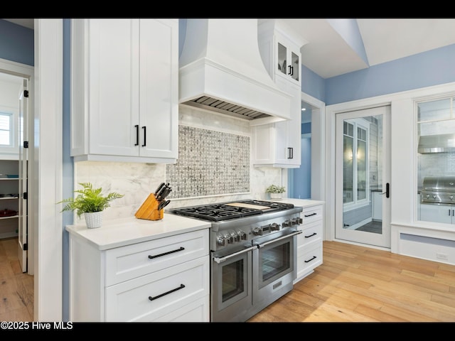 1012 Midnight Channel Rd, Wilmington, NC 28403 - kitchen with range with two ovens, custom exhaust hood, light wood finished floors, backsplash, and light countertops