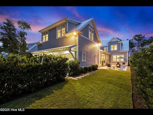 1012 Midnight Channel Rd, Wilmington, NC 28403 - back of house at dusk with a patio, a lawn, and outdoor lounge area