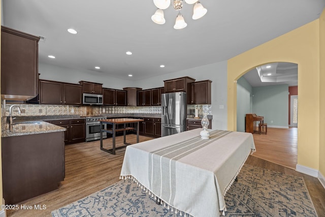 1006 Kingfish Way, New Bern, NC 28562 - kitchen with appliances with stainless steel finishes, a sink, arched walkways, dark brown cabinetry, and decorative backsplash