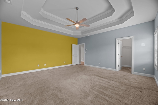 1006 Kingfish Way, New Bern, NC 28562 - unfurnished bedroom with a tray ceiling, ornamental molding, carpet, a walk in closet, and ceiling fan