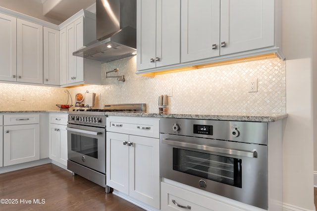 2570 Sugar Maple Ct, Southport, NC 28461 - kitchen with wall chimney exhaust hood, appliances with stainless steel finishes, dark wood-style floors, white cabinetry, and decorative backsplash