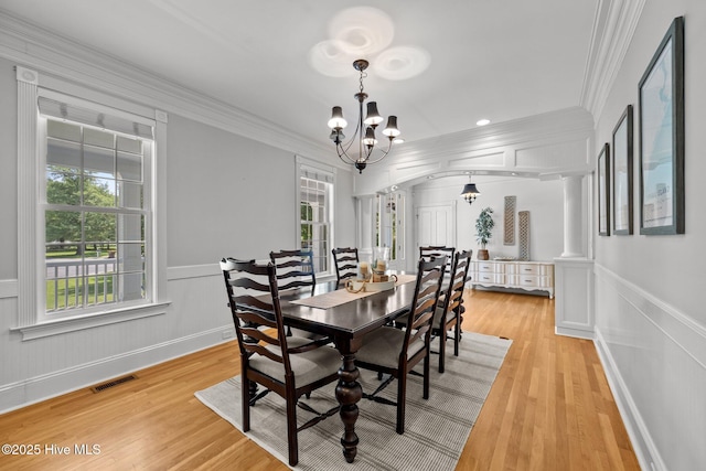 103 Low Country Ct, Hampstead, NC 28443 - dining room featuring crown molding, a chandelier, arched walkways, light wood-style floors, and a wainscoted wall