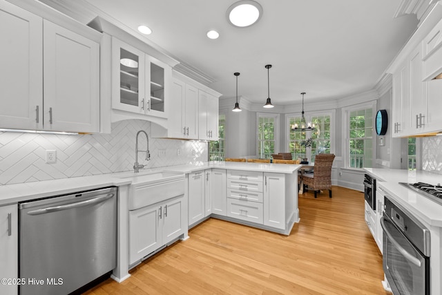 103 Low Country Ct, Hampstead, NC 28443 - kitchen featuring appliances with stainless steel finishes, a sink, a peninsula, white cabinets, and light wood finished floors