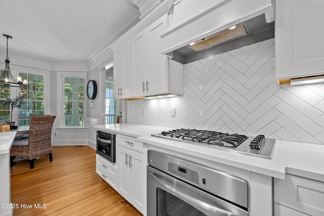 103 Low Country Ct, Hampstead, NC 28443 - kitchen with appliances with stainless steel finishes, custom exhaust hood, light countertops, decorative backsplash, and white cabinetry