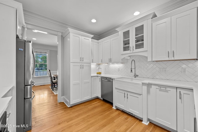 103 Low Country Ct, Hampstead, NC 28443 - kitchen with stainless steel appliances, light wood-style flooring, a sink, white cabinetry, and crown molding