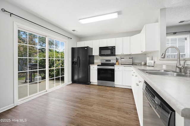 1182 Amber Pines Dr, Leland, NC 28451 - kitchen with black appliances, a sink, light countertops, light wood finished floors, and white cabinets