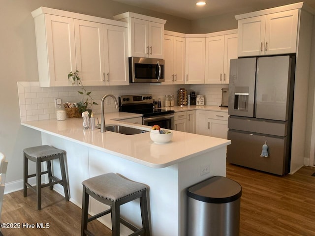4224 Pegasus Pkwy, Leland, NC 28451 - kitchen with appliances with stainless steel finishes, a sink, a peninsula, dark wood-style flooring, and recessed lighting