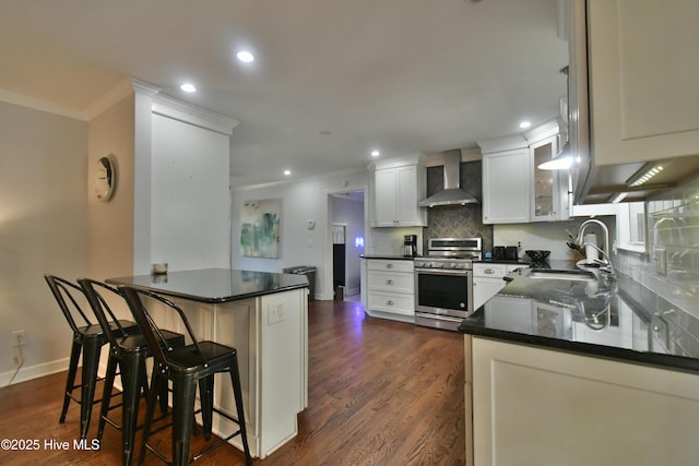 114 Lansdowne Rd, Wilmington, NC 28409 - kitchen featuring stainless steel gas stove, wall chimney range hood, a sink, dark countertops, and crown molding