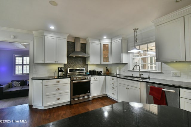114 Lansdowne Rd, Wilmington, NC 28409 - kitchen featuring appliances with stainless steel finishes, wall chimney exhaust hood, a sink, dark countertops, and white cabinetry