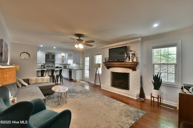 114 Lansdowne Rd, Wilmington, NC 28409 - living area featuring ornamental molding, healthy amount of natural light, a brick fireplace, ceiling fan, and dark wood-style floors