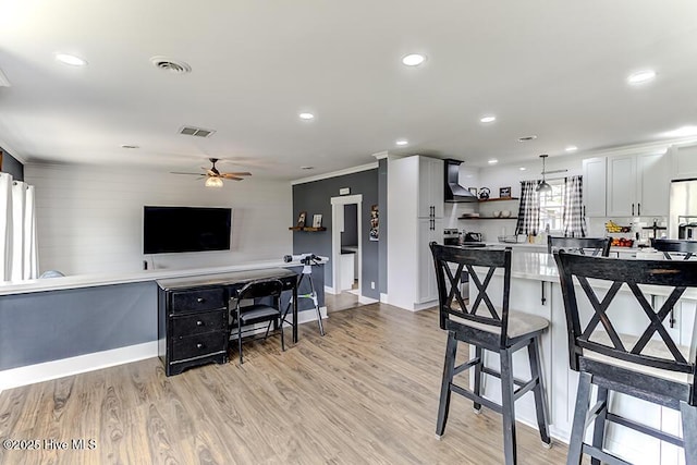 4838 Stillwell Rd, Wilmington, NC 28412 - kitchen with wall chimney exhaust hood, open shelves, a ceiling fan, a kitchen bar, and light wood-style flooring
