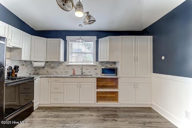 4838 Stillwell Rd, Wilmington, NC 28412 - kitchen with black range with electric cooktop, a sink, stainless steel microwave, a wainscoted wall, and white cabinetry