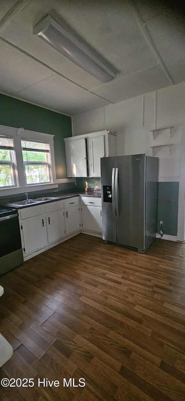 1205 S 7th St, Wilmington, NC 28401 - kitchen with appliances with stainless steel finishes, white cabinetry, dark wood finished floors, dark countertops, and a sink