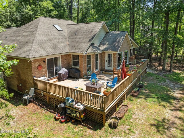 112 Lakeview Ln, Washington, NC 27889 - rear view of property with roof with shingles, brick siding, a wooden deck, and a lawn