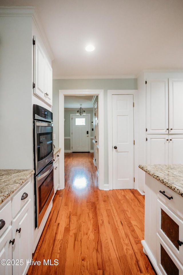 1103 Greenbriar Rd NW, Wilson, NC 27896 - kitchen featuring double oven, light wood-style floors, white cabinetry, crown molding, and light stone counters