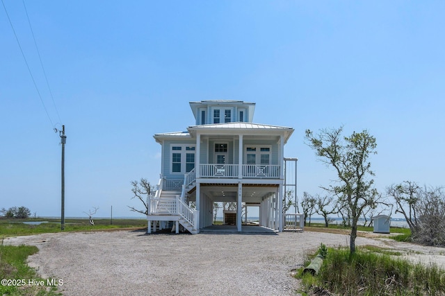 316 Bettie Path Rd, Beaufort, NC 28516 - raised beach house featuring a porch, stairs, a carport, dirt driveway, and metal roof