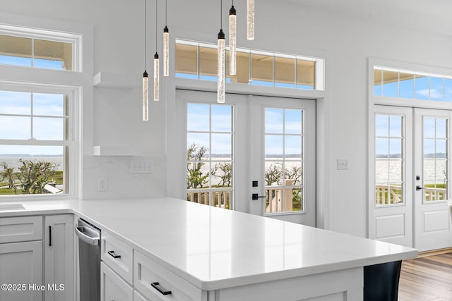 316 Bettie Path Rd, Beaufort, NC 28516 - kitchen with french doors, light countertops, decorative light fixtures, light wood-type flooring, and white cabinetry