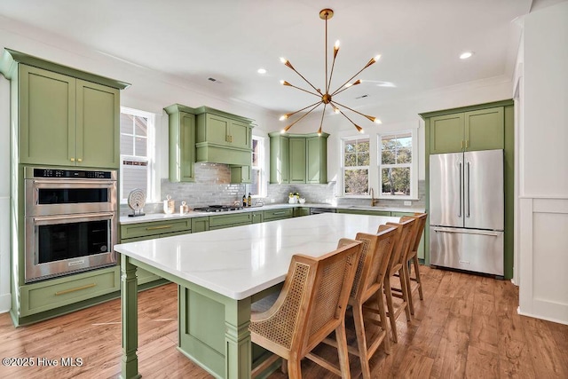 3810 River Park Way NE, Leland, NC 28451 - kitchen with green cabinetry, appliances with stainless steel finishes, a chandelier, a sink, and backsplash