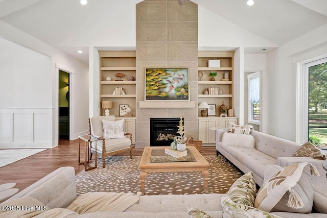3810 River Park Way NE, Leland, NC 28451 - living room featuring wood finished floors, a fireplace, built in shelves, recessed lighting, and a wainscoted wall