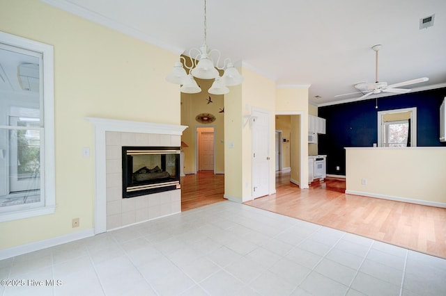 8500 Hammock Dunes Dr, Wilmington, NC 28411 - unfurnished living room with crown molding, a chandelier, a tiled fireplace, a ceiling fan, and light wood-style flooring