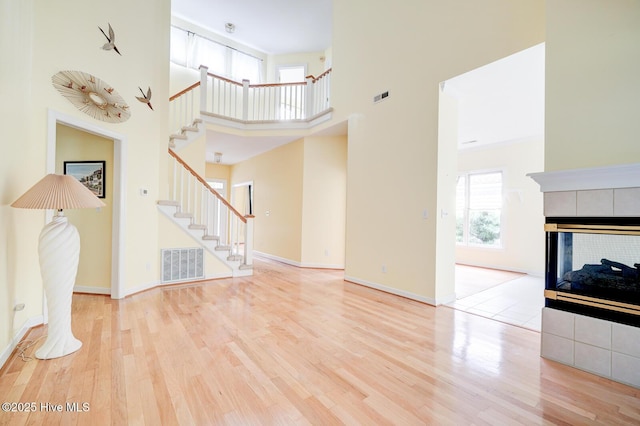 8500 Hammock Dunes Dr, Wilmington, NC 28411 - unfurnished living room featuring stairs, wood finished floors, a towering ceiling, a fireplace, and baseboards