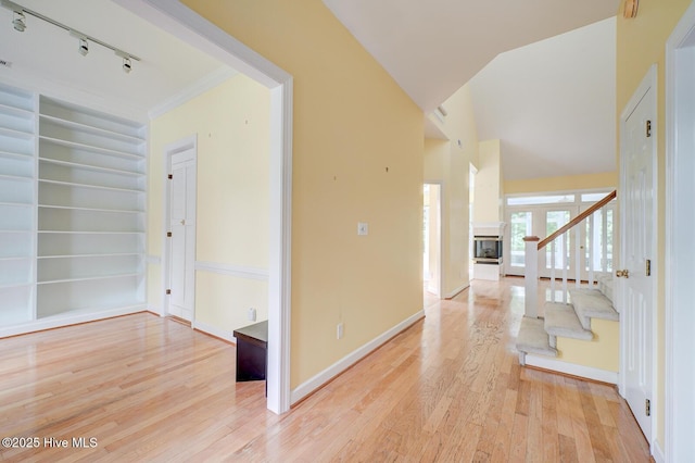 8500 Hammock Dunes Dr, Wilmington, NC 28411 - hallway featuring rail lighting, light wood-type flooring, stairs, built in shelves, and baseboards