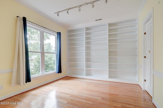 8500 Hammock Dunes Dr, Wilmington, NC 28411 - empty room with rail lighting, light wood-type flooring, healthy amount of natural light, crown molding, and built in shelves