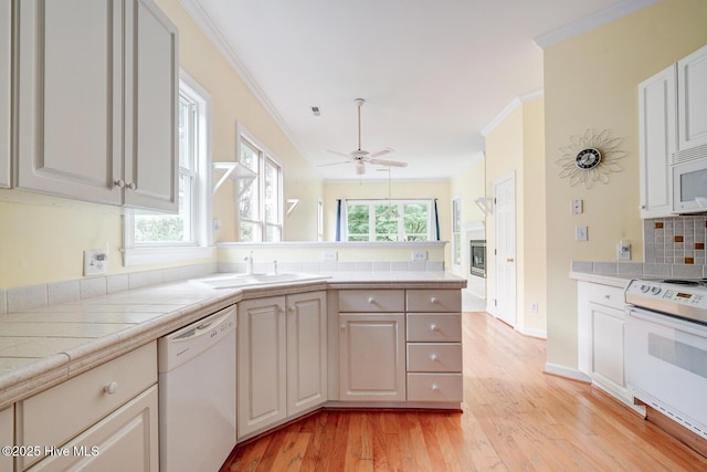 8500 Hammock Dunes Dr, Wilmington, NC 28411 - kitchen with white appliances, a peninsula, light wood-style flooring, a sink, and a ceiling fan